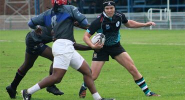 A rugby player is trying to get the ball away from another player.