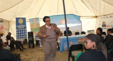 A woman giving a presentation in a tent.