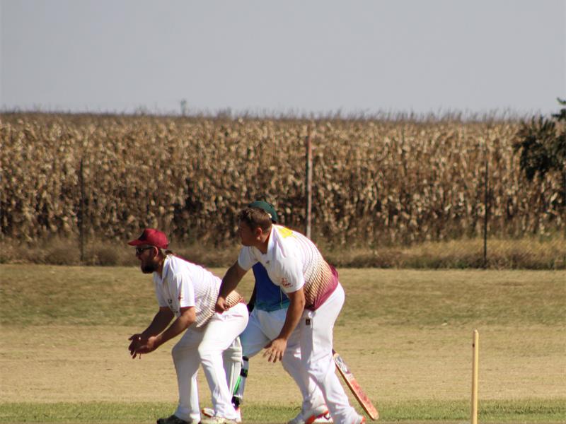 A group of men playing cricket on a field.