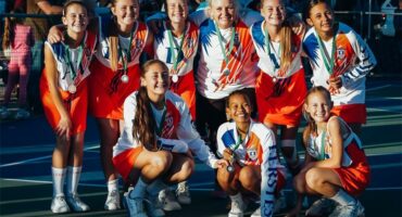 A group of girls in orange and white uniforms posing for a photo.