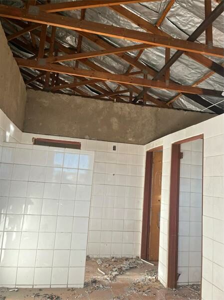 A bathroom with a roof that is being torn down.