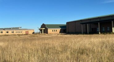 A large building with tall grass in front of it.