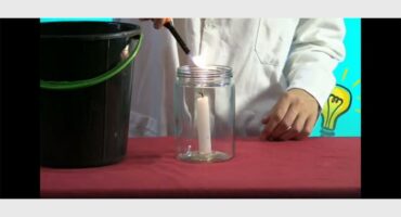 A person is using a candle to light a jar.
