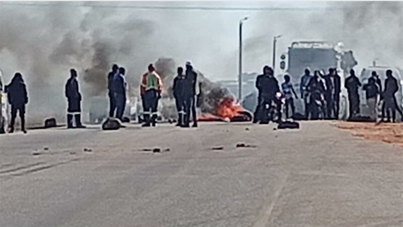 Protesters burn tyres on the road near a truck.