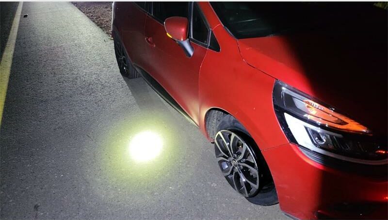 A car is lit up at night with a light on the front.