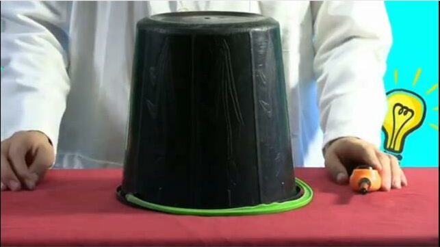 A man is holding a black plastic container on a table.