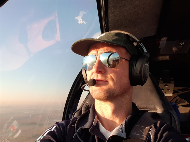 A man wearing sunglasses and a hat is sitting in a helicopter.