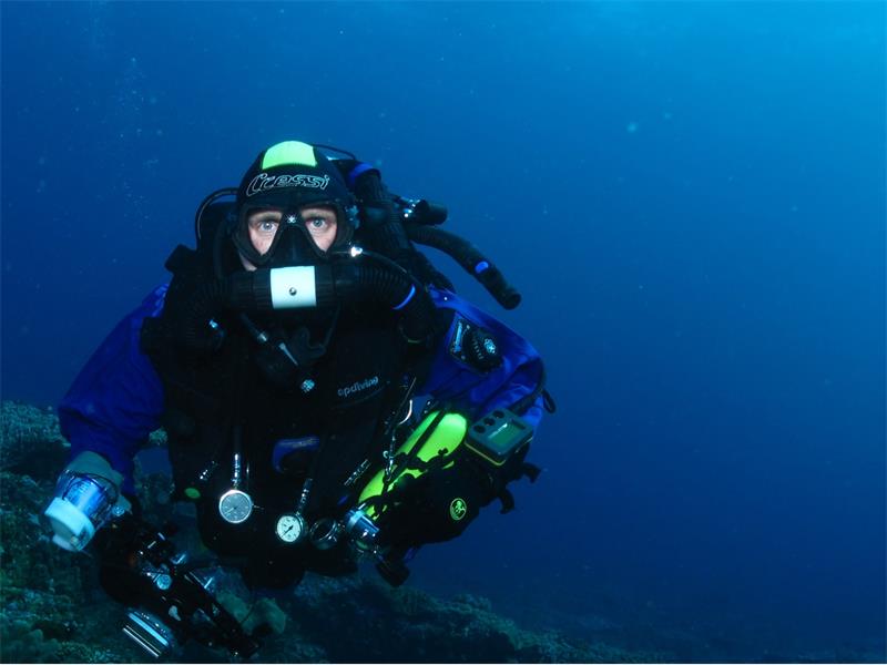 A scuba diver in the water with a camera.