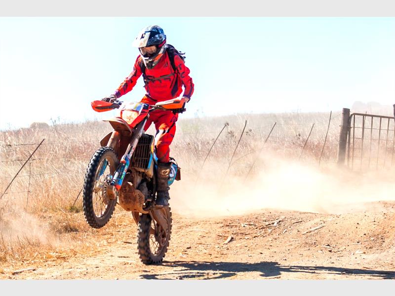 A group of people on dirt bikes in a field.
