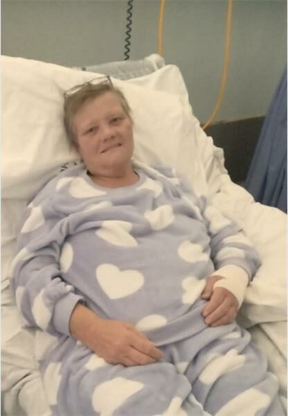 A woman in a hospital bed with a heart shaped blanket.