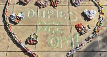 A heart shaped sign with a bunch of cans and bottles.