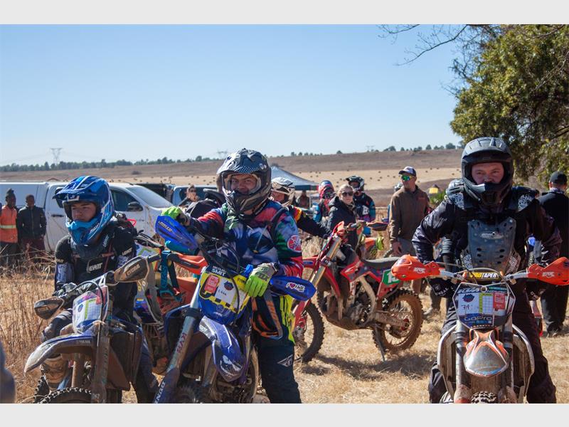 A group of people on dirt bikes in a field.