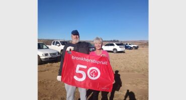 Two people holding a 50th anniversary flag.