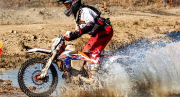 A man riding a dirt bike through a muddy area.