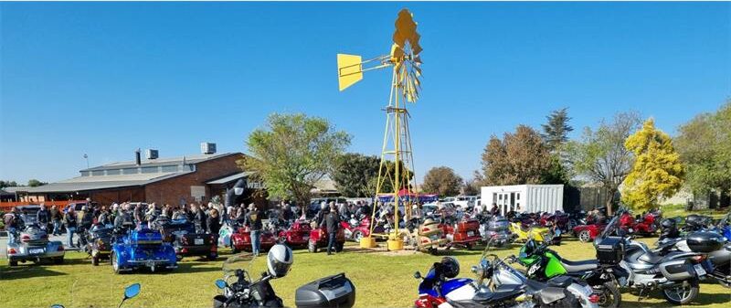 A large group of motorcycles parked in front of a windmill.
