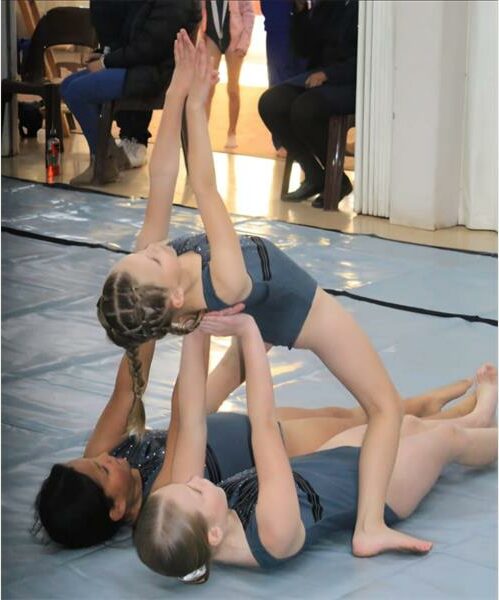 Two girls doing gymnastics on the floor.