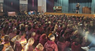 A large crowd of people in a school auditorium.