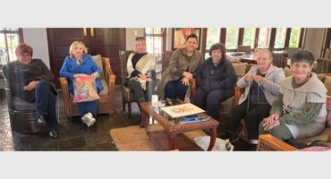 A group of people sitting around a table in a living room.