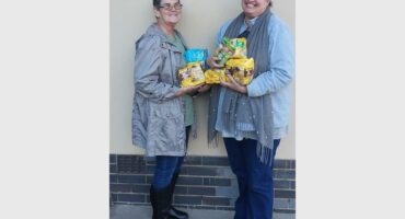 Two women holding up a box of noodles