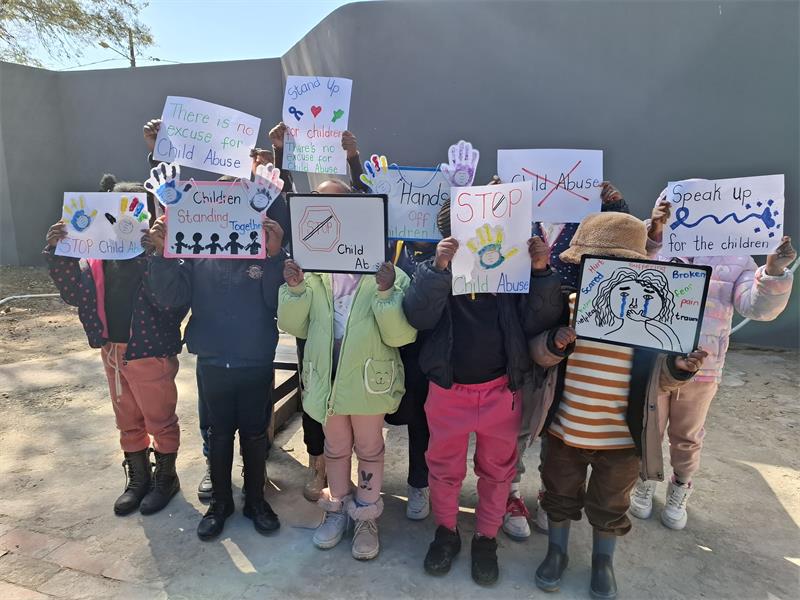 Children holding up signs in front of a building.