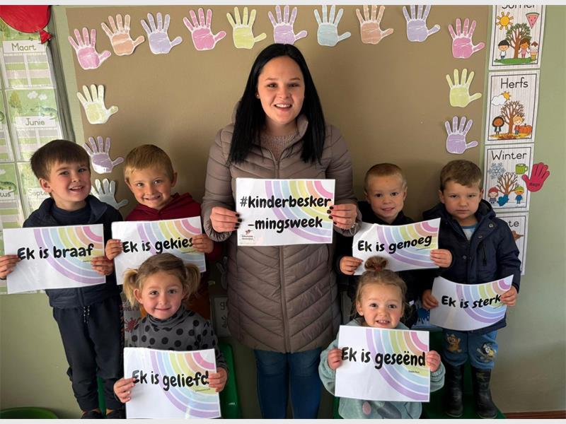 A woman holding up a sign with children in front of her.