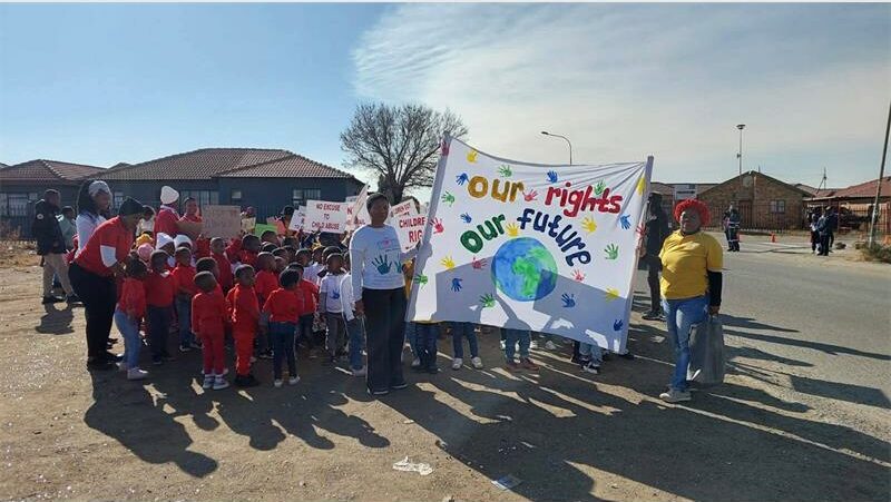 A group of people holding a banner in front of a house.