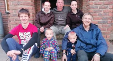 A family poses for a photo outside their home.