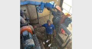 A man standing next to a machine that is used to make cement.