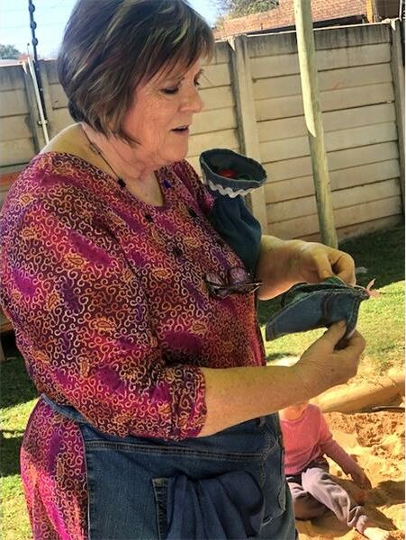 An older woman standing next to a cake.