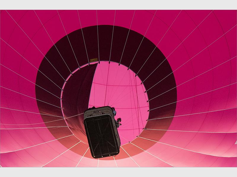 A pink hot air balloon with a person inside.