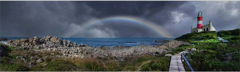A rainbow over the ocean and lighthouse.