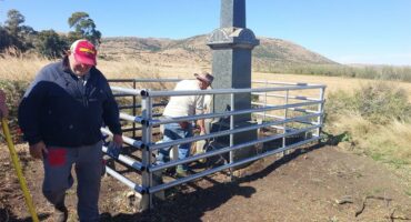 Two men are working on a fence near a monument.