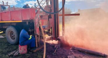 A man is working on a machine that is pumping red dust.