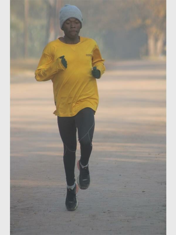 A man in yellow shirt and black pants running.
