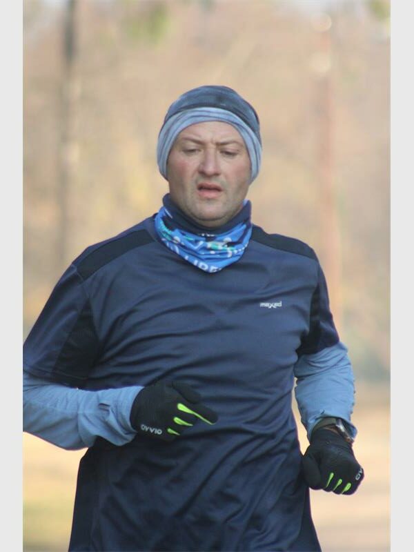 A man wearing a blue hat and gloves runs.