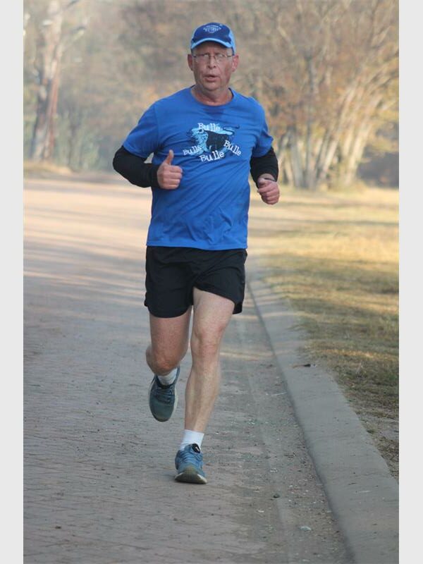 A man in a blue shirt and black shorts running.