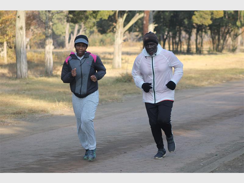 Two people jogging on a paved road.
