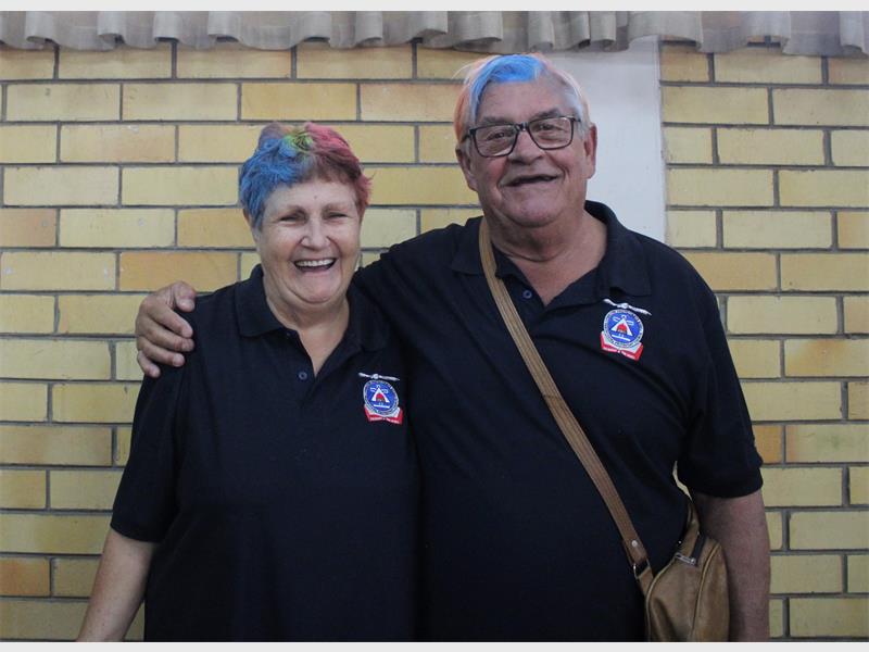 An older couple with blue hair posing for a picture.