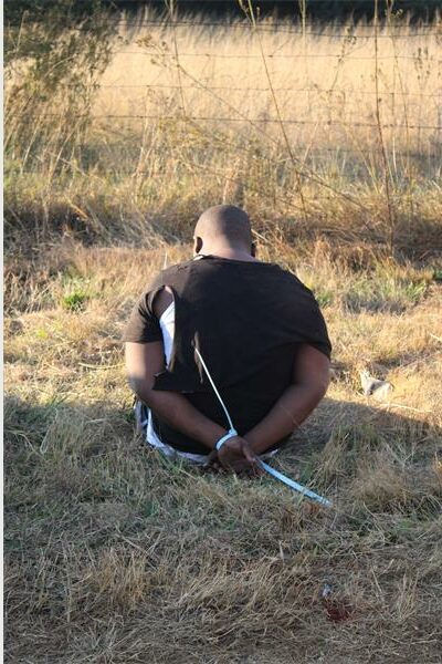 A man sitting on the ground with a knife.