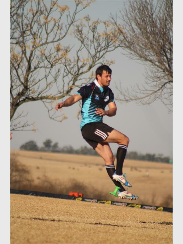 A man in a blue shirt is kicking a soccer ball.