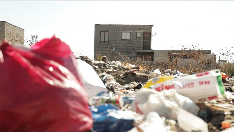 A pile of garbage and trash in front of a house.