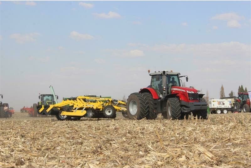 A tractor and a combine are working in a field.