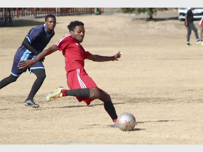 A man in red kicking a soccer ball.