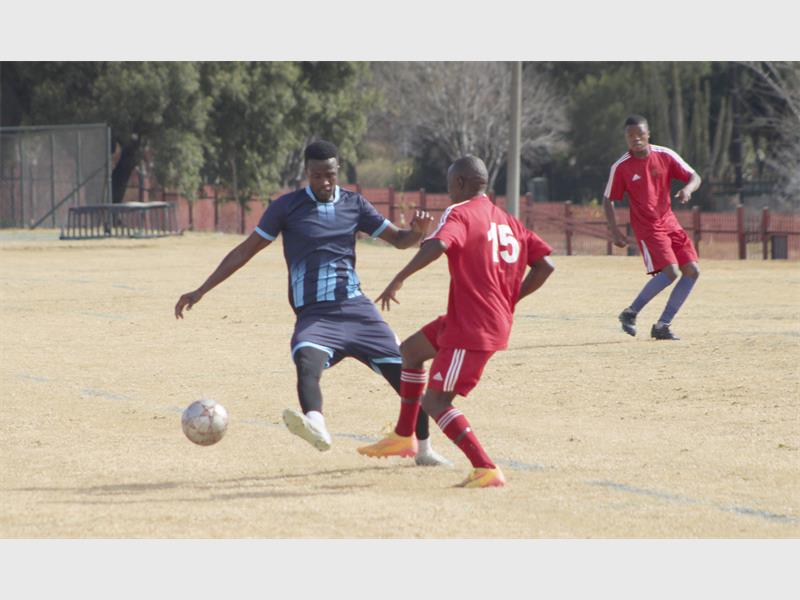 Two men in red and blue uniforms playing soccer.
