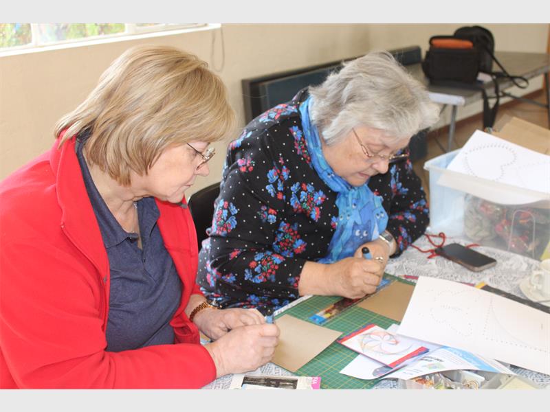 Two women working on crafts at a table.