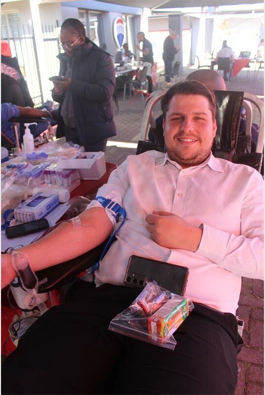 A man sitting in a chair with a blood bag.
