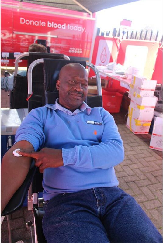 A man sitting in a chair with a blood bag.