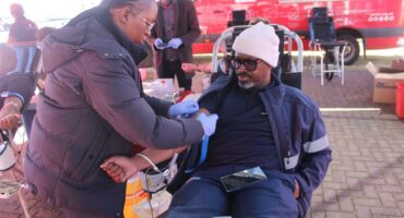 A woman preparing a man who's about donate blood at the donor centre.