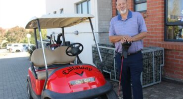 A man standing next to a red golf cart.