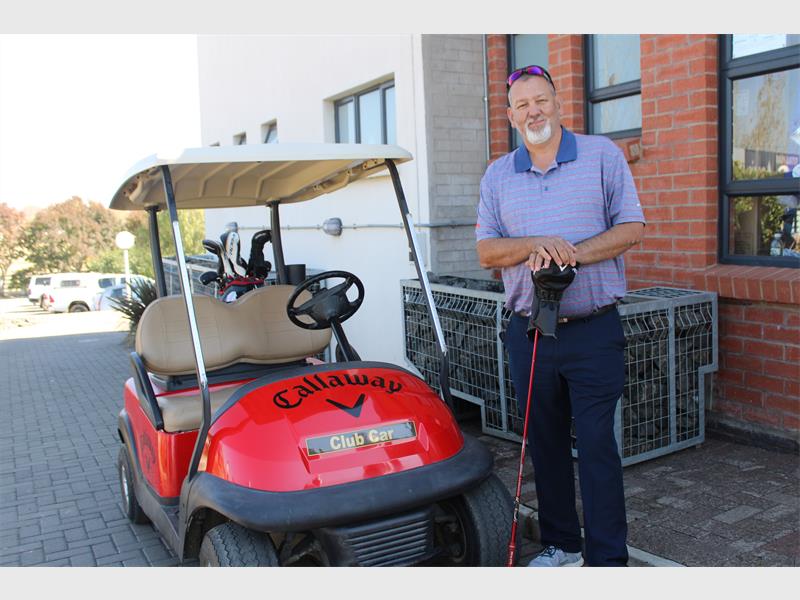 A man standing next to a red golf cart.